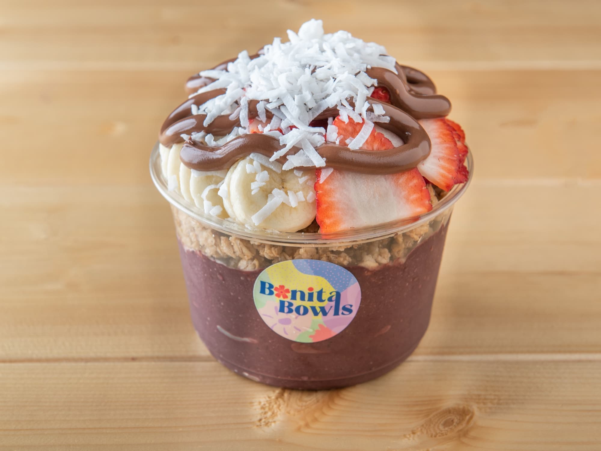 A vibrant purple açaí bowl topped with granola, fresh fruit, and honey